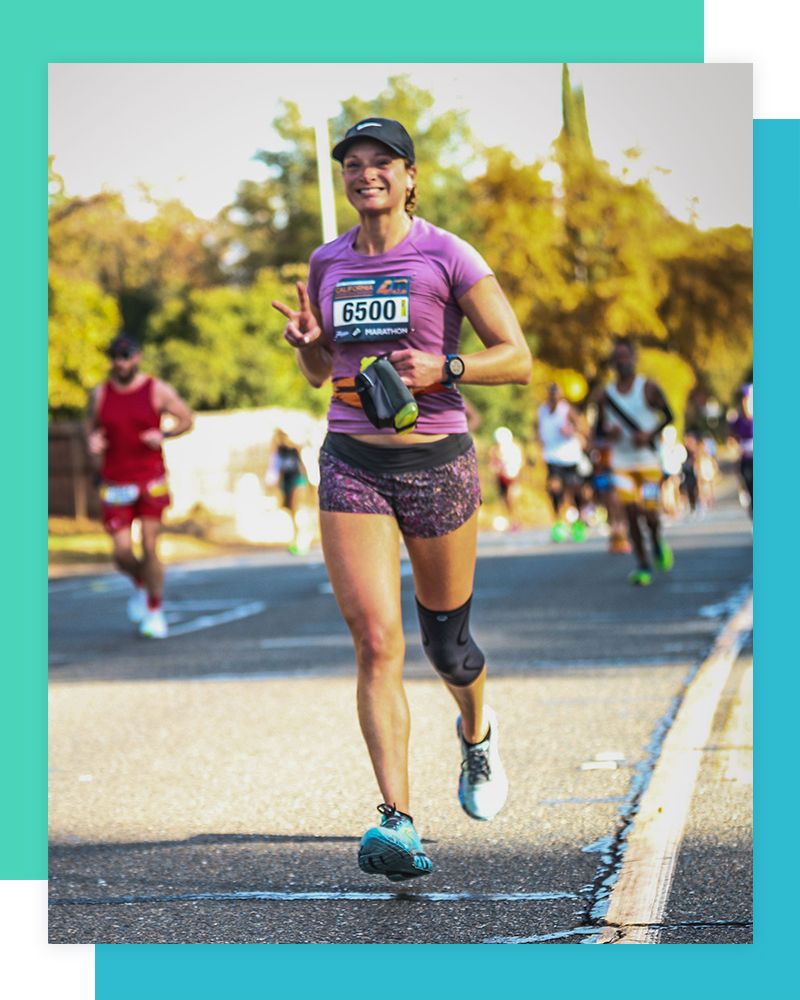 Running coach Nicole smiling and giving a peace sign during a marathon